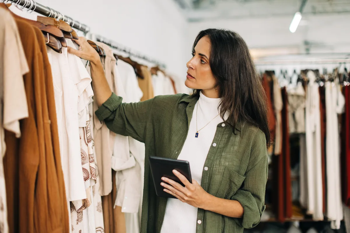 Boutique owner arranging clothing racks