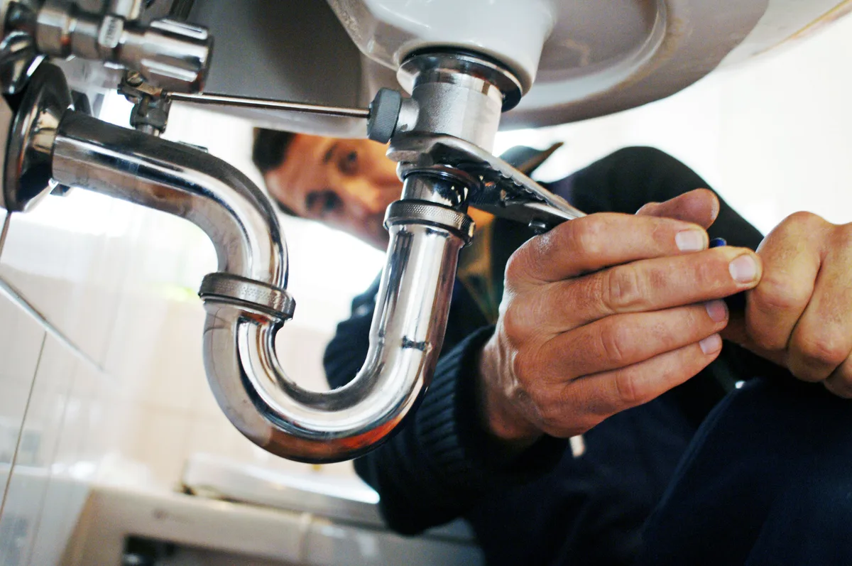 Plumber repairing pipes under a sink