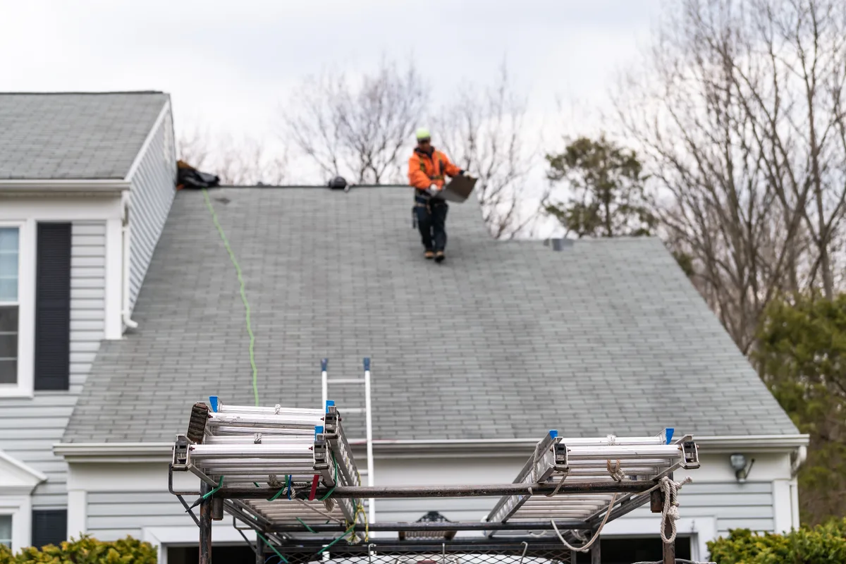 Roofer installing shingles on a residential roof