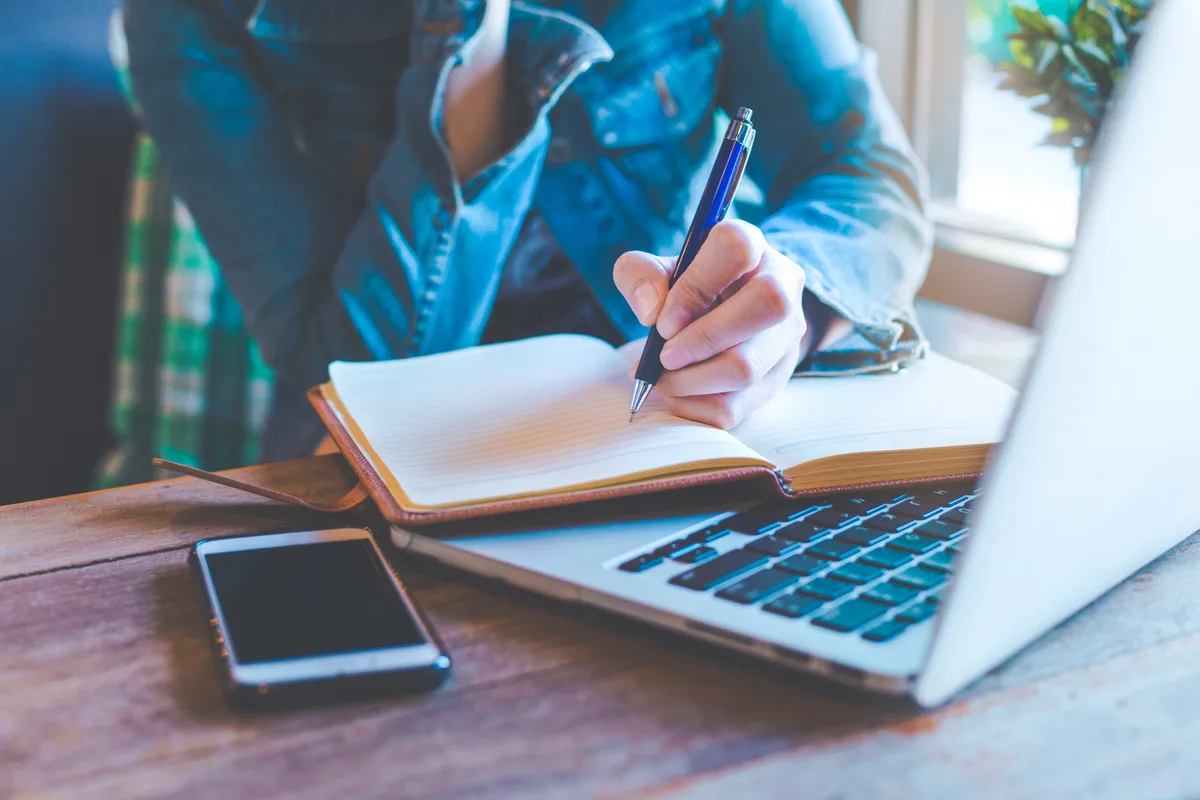 Author writing at a laptop beside books