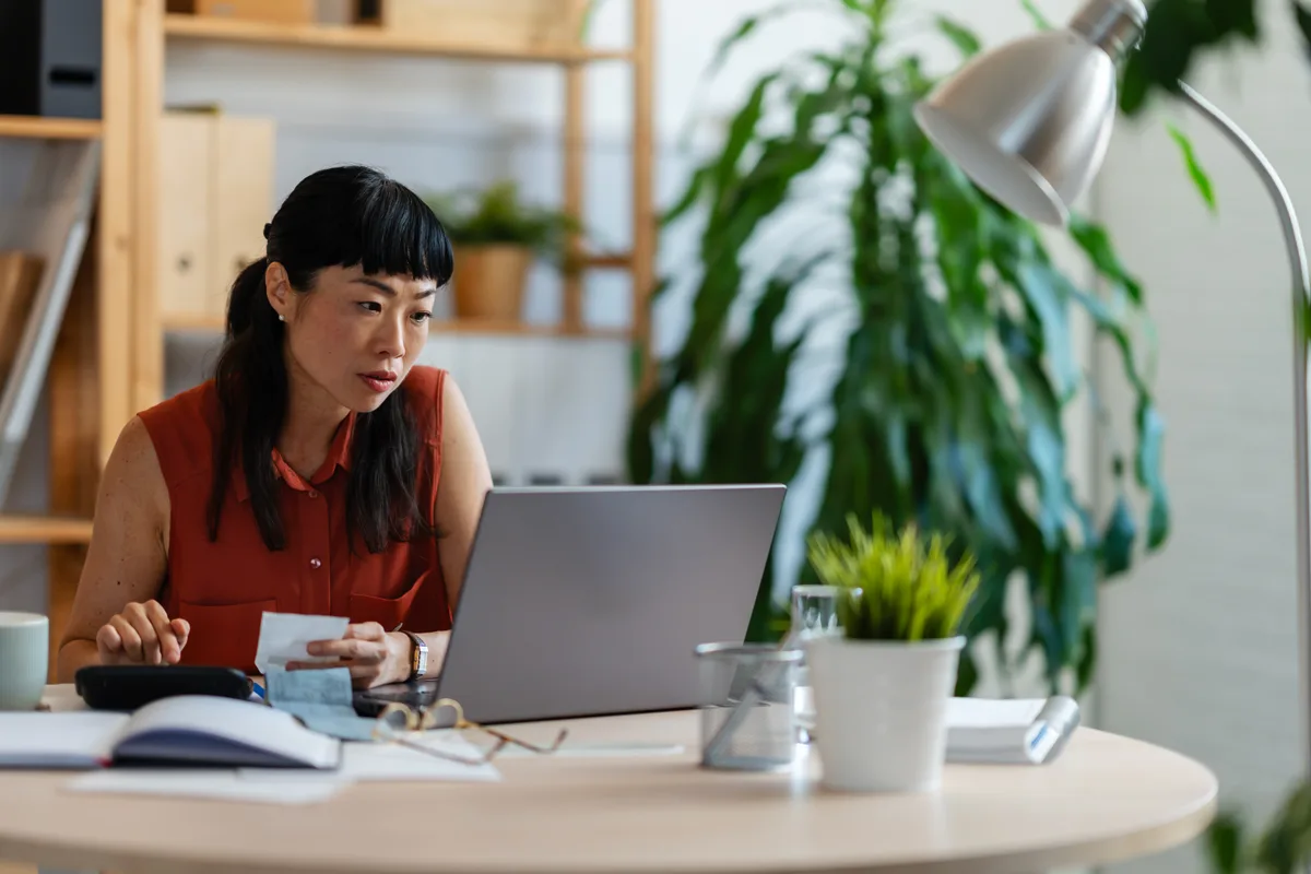 A bookkeeper checking receipts against the ledger at her desk