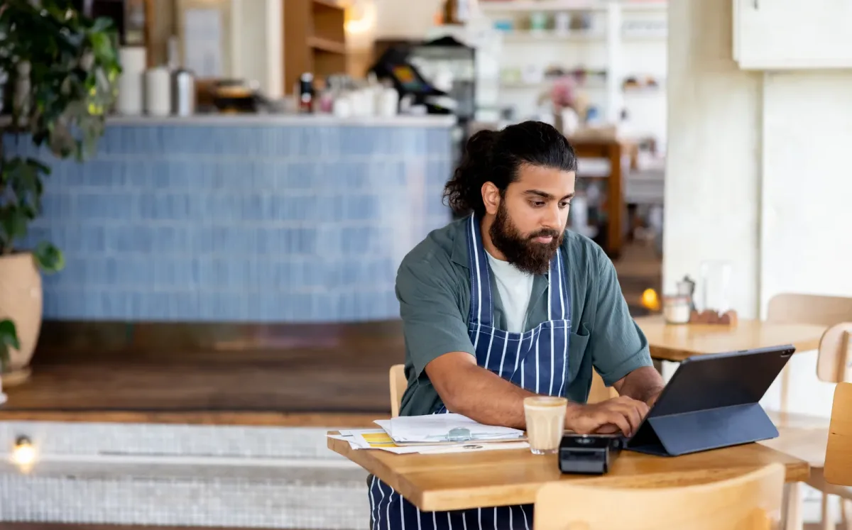 A café owner working through the books on a laptop at the counter