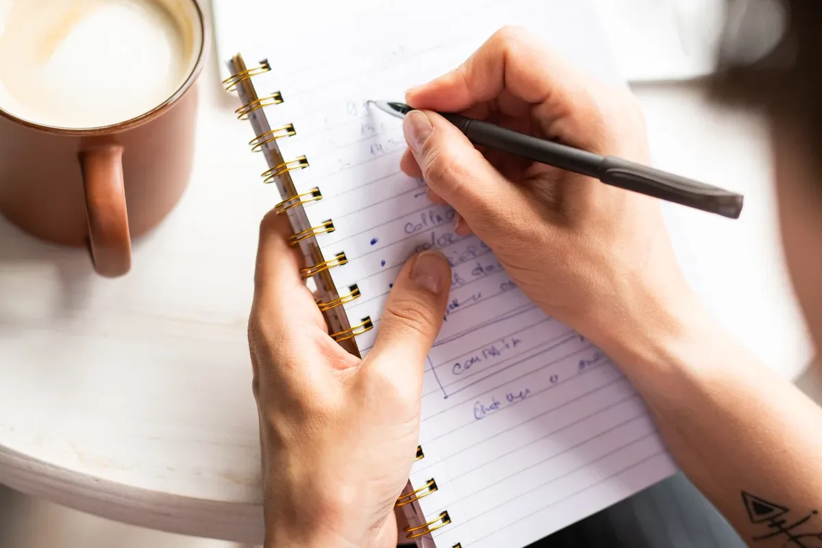 Writing up the month’s entries by hand beside a morning coffee