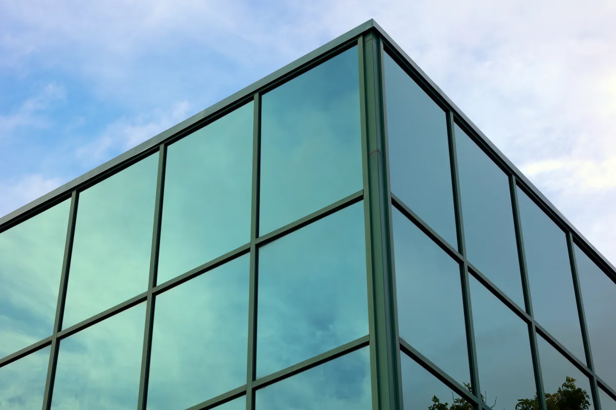 A glass office tower against a clear sky