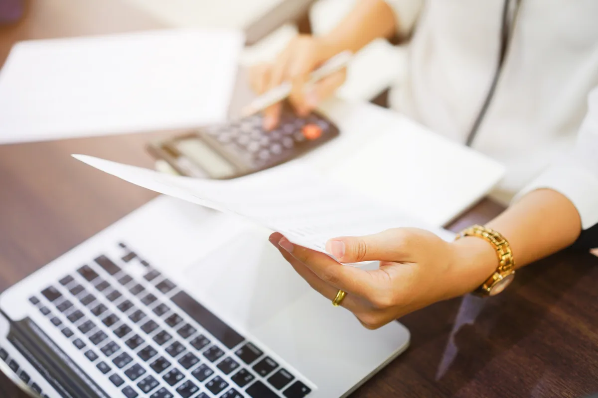 Processing payroll with a calculator and a laptop