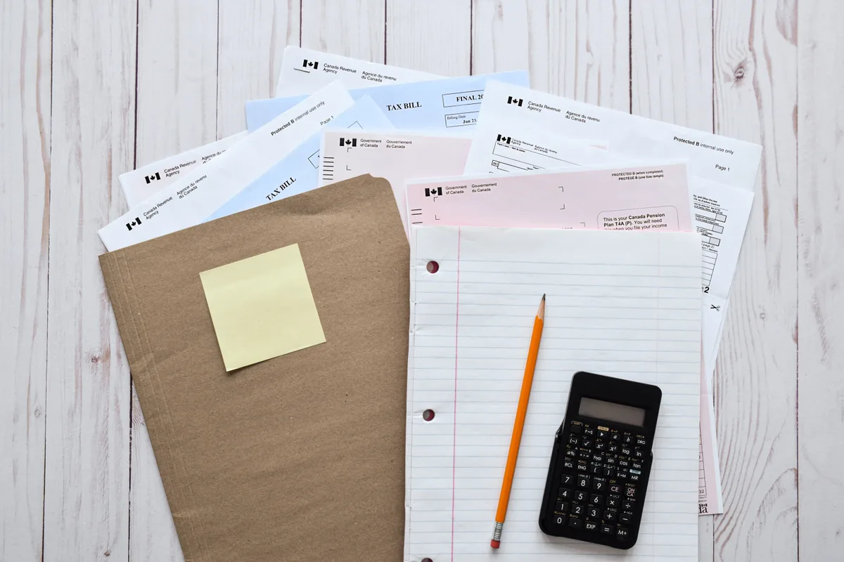 Tax slips, a folder and a calculator laid out on a desk